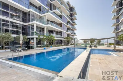a swimming pool in front of a building at Cozy Studio in Orchid - Damac Hills Dubai in Dubai