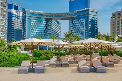 a row of chairs and umbrellas on a beach at Beachfront 1BR Seven Palm Rooftop Pool & Views in Dubai