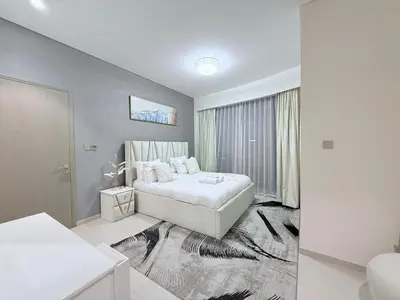 a white bedroom with a bed and a window at Skyline Escape 2BR with Balcony Pool & Gym in Dubai