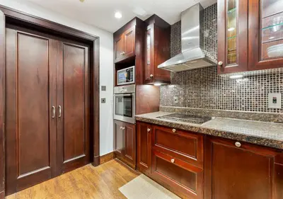 a kitchen with wooden cabinets and a counter top at 2BR Downtown Dubai 5 Min Walk to Dubai Mall & Burj in Dubai