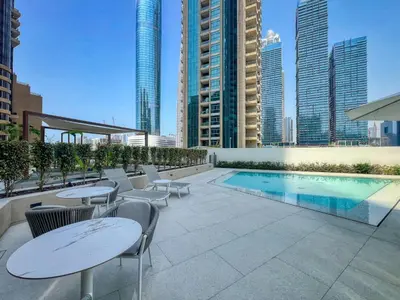 a rooftop patio with tables and chairs and a pool at Modern Waterfront Living with Stunning Views in Dubai