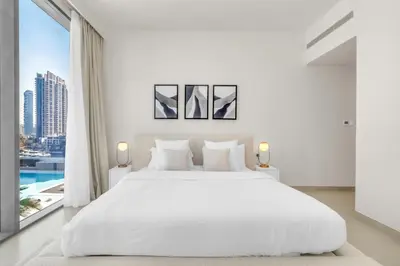 a white bedroom with a large bed and a large window at Modern Waterfront Living with Stunning Views in Dubai