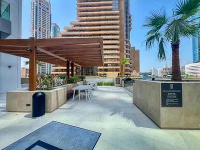 a patio with a table and chairs and a large building at Stylish Coastal Living with Premium Amenities in Dubai
