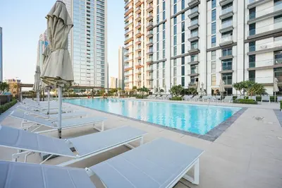 a swimming pool with lounge chairs and an umbrella at DVH Luxe Retreats 2 Bedroom Downtown by Burj Khalifa and Dubai Mall in Dubai