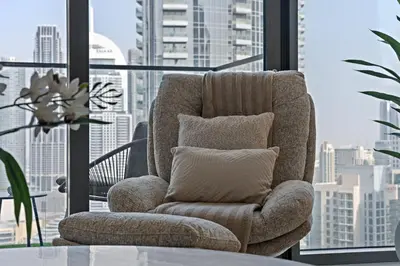 a chair with a pillow in a room with a window at DVH Luxe Retreats 2 Bedroom Downtown by Burj Khalifa and Dubai Mall in Dubai