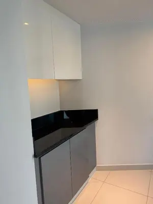 a kitchen with white cabinets and a black counter top at Royal Montania by DAMAC Maison Prive in Dubai