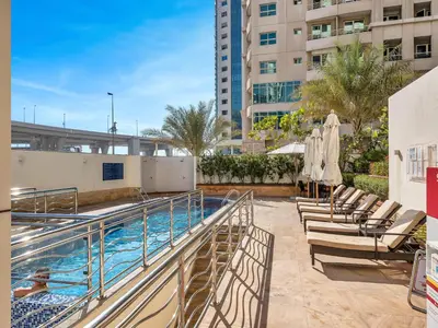 a swimming pool with chaise lounge chairs next to a building at Luxury 5 Star Newly Furnished 3BR Apartment in Dubai Marina in Dubai