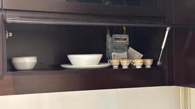 a cabinet with bowls and cups on a shelf at LUX 1BR 5 Min Walk Dubai Mall - DAMAC Upper Crest in Dubai