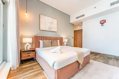 a bedroom with a large bed and a table with a lamp at Stunning 1BR with Panoramic Canal Views, Convenient Downtown Access and Walking Distance to Bus Stop, J One - 1, Business Bay by Deluxe Holiday Homes in Dubai