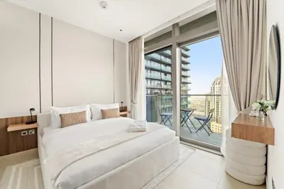 a white bedroom with a large bed and a balcony at FIRST CLASS 1BR Breathtaking Marina Views in Dubai