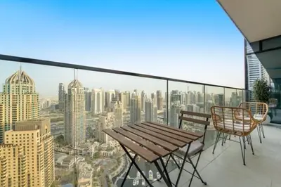 a balcony with a wooden table and chairs and a city at FIRST CLASS 1BR Breathtaking Marina Views in Dubai