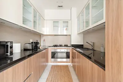 a large kitchen with wooden cabinets and appliances at FIRST CLASS 3BR Comfort and Style , Business Bay in Dubai
