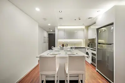 a kitchen with a white table and white appliances at FIRST CLASS 1BR Marina Skyline Escape in Dubai
