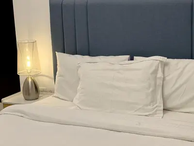 a bed with white pillows and a lamp on a table at Stylish 1BR Canal View Apartment Business Bay in Dubai
