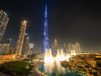 a city with a fountain in front of a tall building at Panoramic Burj 5br Condo with Full Led & Fountain View in Dubai