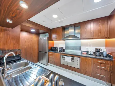 a kitchen with wooden cabinets and stainless steel appliances at Panoramic Burj 5br Condo with Full Led & Fountain View in Dubai
