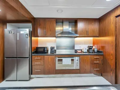 a kitchen with wooden cabinets and a stainless steel refrigerator at Panoramic Burj 5br Condo with Full Led & Fountain View in Dubai