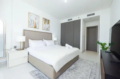 a white bedroom with a large bed and a television at Modern & Luxurious 2BR Penthouse in MBR City District One Dubai in Dubai