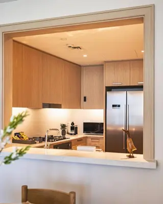 a kitchen with a stainless steel refrigerator and wooden cabinets at The Opera Grand Ultra Luxury Suite Burj Khalifa and Fountain View in Dubai