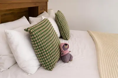 a stuffed teddy bear sitting on a bed with pillows at Marina 2BR 58th Floor Sea and City Views Pool Gym in Dubai