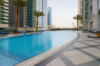 a large swimming pool with palm trees and buildings at Marina 2BR 58th Floor Sea and City Views Pool Gym in Dubai