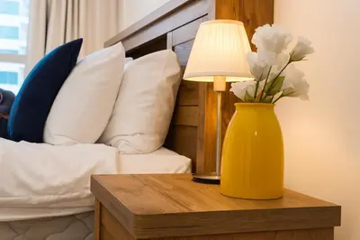 a yellow vase of flowers on a table with a lamp at Marina 2BR 58th Floor Sea and City Views Pool Gym in Dubai