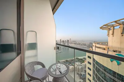 a balcony with two chairs and a view of a city at Elegant 2BR with Panoramic Marina View in Dubai