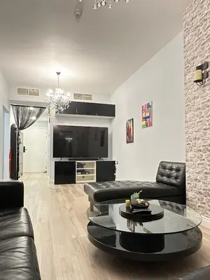 a living room with a black leather couch and a table at JLT Luxury New 2BHK in Dubai