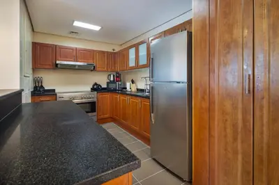 a kitchen with wooden cabinets and a stainless steel refrigerator at Luxury JLT 1BR 2 Beds in Room Lakeview & Pool in Dubai