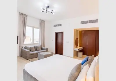 a white bedroom with a bed and a couch at Comfort Ensuite with Balcony in Dubai