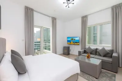 a white bedroom with a bed and a couch at Comfort Ensuite with Balcony in Dubai