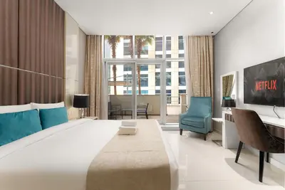 a bedroom with a large bed with a blue chair at Poolside Studio with Canal Views and Near Dubai Mall in Dubai