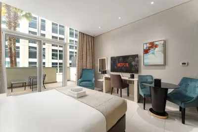 a hotel room with a bed and a desk and chairs at Poolside Studio with Canal Views and Near Dubai Mall in Dubai