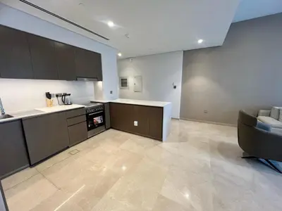 a kitchen with brown cabinets and a couch in a room at Grande in Dubai
