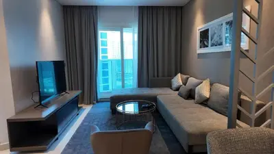 a living room with a couch and a tv at Damac Maison Prive in Dubai