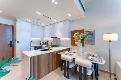 a kitchen with white cabinets and a table with chairs at Cozy Apartment Gym and Pool Heart of JVC in Dubai