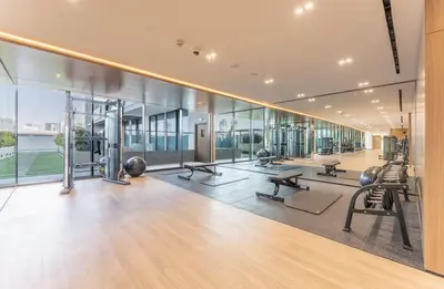 an empty gym with exercise equipment and glass walls at Cozy Apartment Gym and Pool Heart of JVC in Dubai