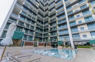 a large apartment building with a swimming pool and chairs at Cozy Apartment Gym and Pool Heart of JVC in Dubai