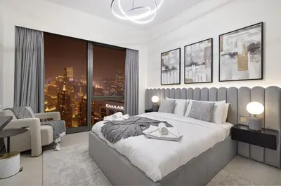 a bedroom with a large bed and a chair and a window at Grande Altura Burj & Fountain view 57 floor in Dubai