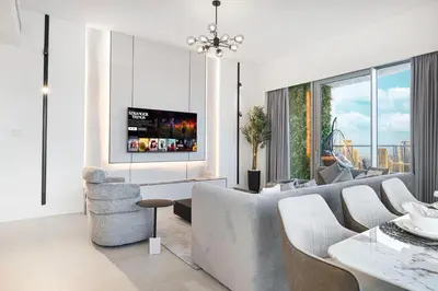 a living room with a couch and a tv on a wall at Grande Altura Burj & Fountain view 57 floor in Dubai