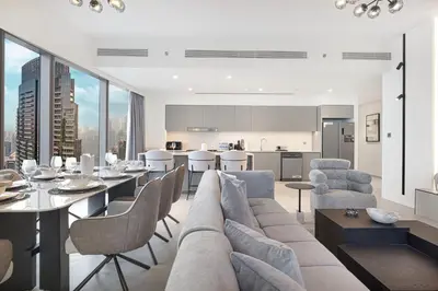 a living room with a couch and a table with chairs at Grande Altura Burj & Fountain view 57 floor in Dubai