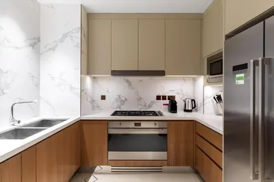 a kitchen with wooden cabinets and a stainless steel refrigerator at Maison Privee - Fabulous Apt with Sensational Burj Khalifa Views in Dubai