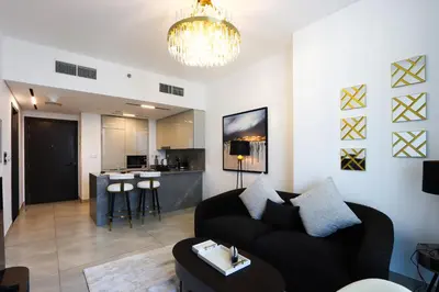 a living room with a black couch and a kitchen at 1BR Paragon Tower Burj Khalifa & Canal Views in Dubai