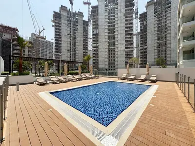 a swimming pool with chaise lounges and chairs and buildings at Modern & Elegant Studio Apartment in Azizi Riviera in Dubai