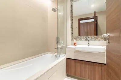 a bathroom with a tub and a sink and a mirror at Silkhaus Lavish 3BDR+Maid Room Imperial Avenue in Dubai