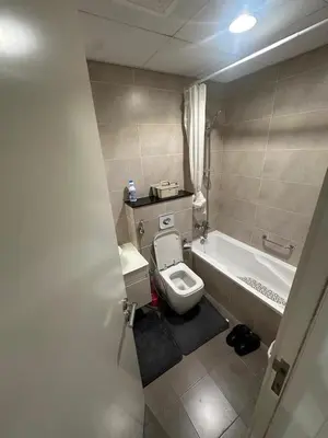 a bathroom with a toilet and a bath tub at Carson Tower- A Damac Hills 1, Studio Apartment in Dubai