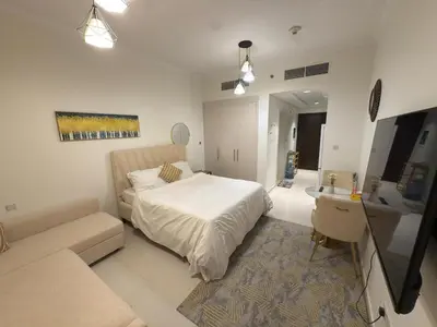 a bedroom with a white bed and a couch at Carson Tower- A Damac Hills 1, Studio Apartment in Dubai