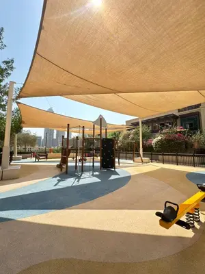 a pavilion with awning over a playground with a yellow bench at Souk Al Bahar Lavish 1-bedroom apartment with Burj Khalifa view at your doorstep by Norbu Holiday Homes in Dubai