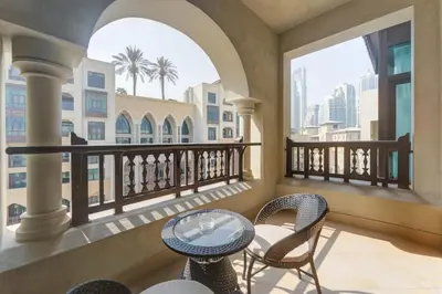 a balcony with a table and chairs and windows at Souk Al Bahar Lavish 1-bedroom apartment with Burj Khalifa view at your doorstep by Norbu Holiday Homes in Dubai
