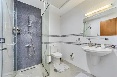 a bathroom with a shower and a toilet and a sink at Modern 2BR in Ikarus Tower, Dubai Production City in Dubai